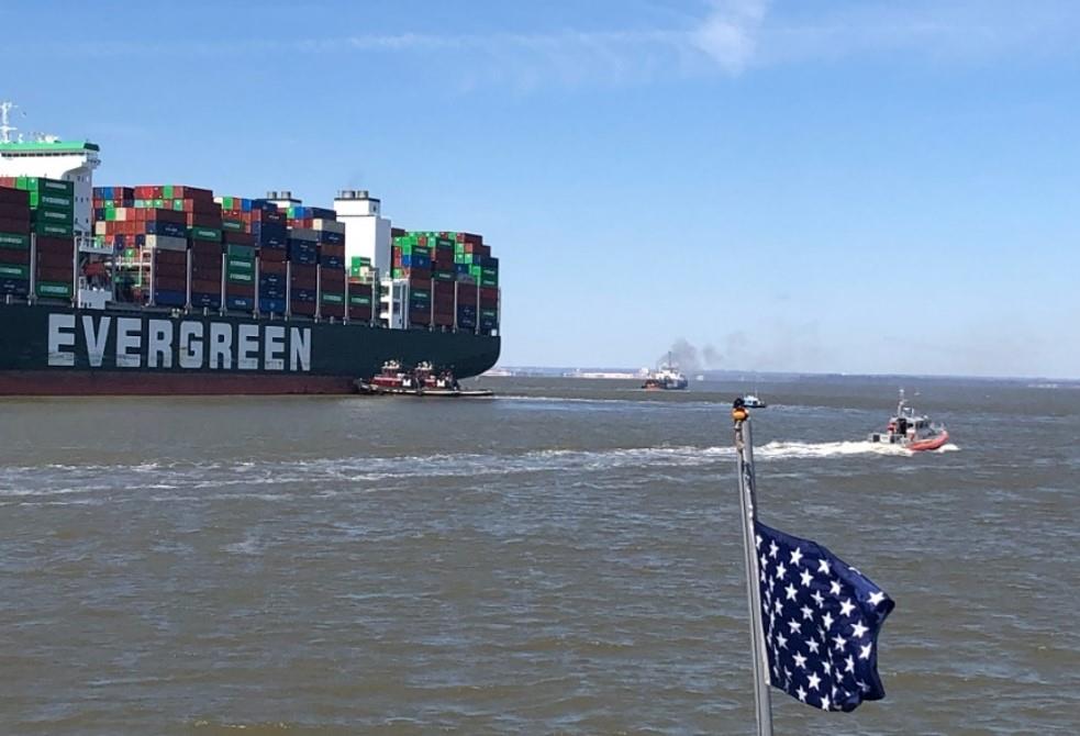 the container ship Evergreen underway with several nearby ships and a blue flag with stars in the foreground